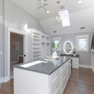 Ejemplo de armario vestidor unisex, de estilo de casa de campo, grande, con armarios abiertos, puertas de armario blancas, suelo de madera clara y suelo marrón