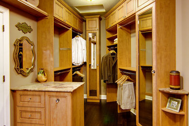 Inspiration for a large timeless dark wood floor and brown floor walk-in closet remodel in Minneapolis with medium tone wood cabinets and recessed-panel cabinets