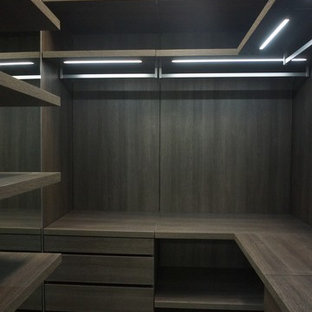 Modelo de armario vestidor de hombre, minimalista, pequeño, con puertas de armario de madera en tonos medios y suelo de baldosas de porcelana