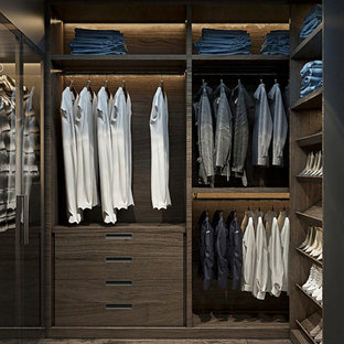 Ejemplo de armario vestidor unisex, minimalista, grande, con armarios con paneles lisos, puertas de armario de madera en tonos medios, suelo de madera oscura y suelo marrón