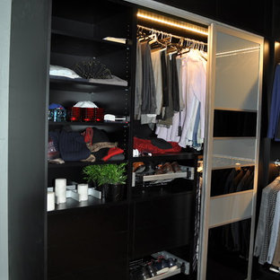 Ejemplo de vestidor de hombre, moderno, pequeño, con armarios con paneles lisos, puertas de armario negras, suelo de cemento y suelo gris