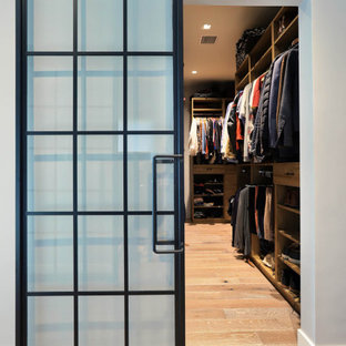 Idee per una grande cabina armadio unisex industriale con ante lisce, ante in legno scuro, parquet chiaro e pavimento beige