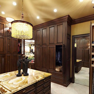 Modelo de vestidor unisex, clásico, grande, con armarios con paneles empotrados, puertas de armario de madera en tonos medios y suelo de piedra caliza
