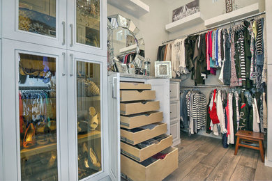 Ejemplo de armario vestidor de mujer moderno grande con armarios tipo vitrina, puertas de armario blancas y suelo marrón
