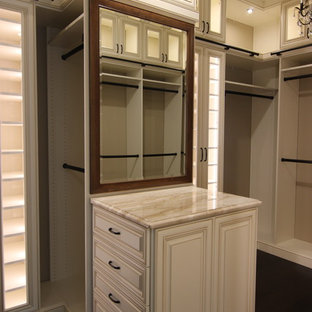 Imagen de armario vestidor clásico, grande, con armarios con paneles con relieve, puertas de armario beige, suelo de madera oscura y suelo marrón