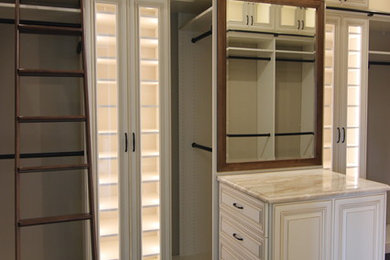 Modelo de armario vestidor tradicional grande con armarios con paneles con relieve, puertas de armario beige, suelo de madera oscura y suelo marrón