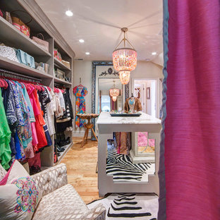 Réalisation d'un dressing room bohème de taille moyenne pour une femme avec des portes de placard grises, un sol en bois brun et un placard sans porte.