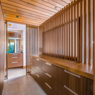 Ejemplo de armario vestidor unisex, moderno, de tamaño medio, con armarios con paneles lisos, puertas de armario de madera oscura, suelo de baldosas de cerámica y suelo gris