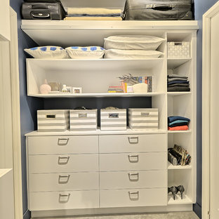 Immagine di una piccola cabina armadio unisex chic con ante lisce, ante bianche e pavimento in cemento