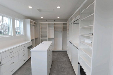 Ejemplo de armario vestidor unisex de estilo americano grande con armarios con paneles lisos, puertas de armario blancas, moqueta y suelo gris