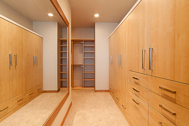 Diseño de armario vestidor contemporáneo con puertas de armario de madera clara y moqueta