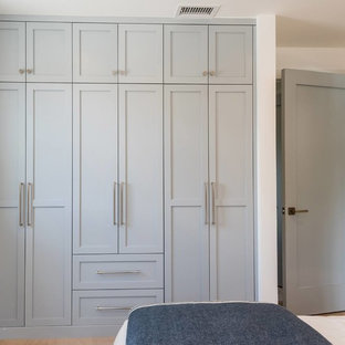 Esempio di un piccolo armadio o armadio a muro unisex costiero con ante in stile shaker, ante blu, pavimento in legno massello medio e pavimento marrone
