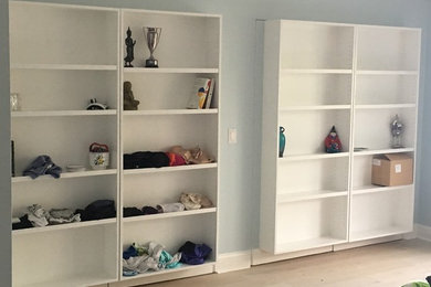 Example of a mid-sized beach style gender-neutral reach-in closet design in Miami with flat-panel cabinets and white cabinets