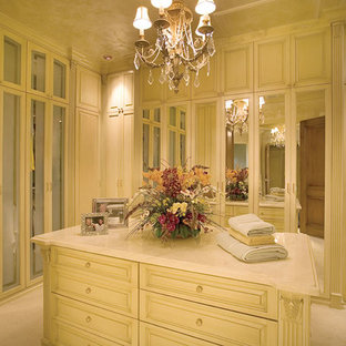 Immagine di un'ampia cabina armadio per donna mediterranea con ante beige e moquette
