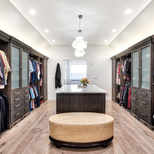 Ispirazione per un'ampia cabina armadio unisex classica con ante lisce, ante in legno bruno e parquet chiaro