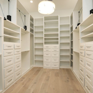 Foto de armario vestidor unisex, campestre, grande, con armarios estilo shaker, puertas de armario blancas y suelo de madera clara