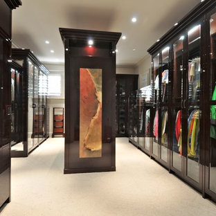 Ispirazione per un'ampia cabina armadio unisex contemporanea con ante di vetro, ante in legno bruno e moquette