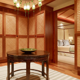 Inspiration pour un dressing room ethnique avec un placard à porte plane et des portes de placard en bois brun.