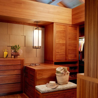 Walk-in closet - tropical gender-neutral medium tone wood floor and brown floor walk-in closet idea in Hawaii with louvered cabinets and medium tone wood cabinets