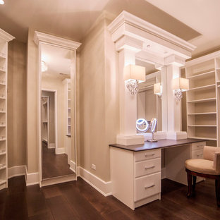 Cette photo montre un très grand dressing chic pour une femme avec un placard à porte plane, des portes de placard blanches et un sol en bois foncé.
