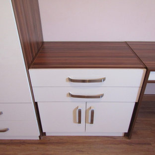 Inredning av ett modernt stort klädskåp för könsneutrala, med släta luckor, beige skåp, laminatgolv och brunt golv