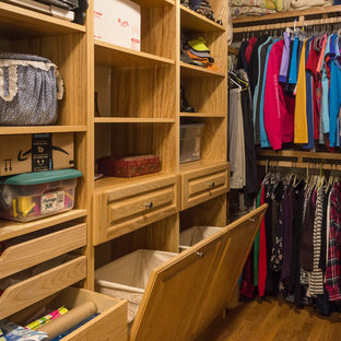 Ispirazione per una cabina armadio unisex stile americano di medie dimensioni con ante con bugna sagomata, ante in legno chiaro, pavimento in legno massello medio e pavimento marrone