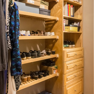 Esempio di una cabina armadio unisex american style di medie dimensioni con ante con bugna sagomata, ante in legno chiaro, pavimento in legno massello medio e pavimento marrone
