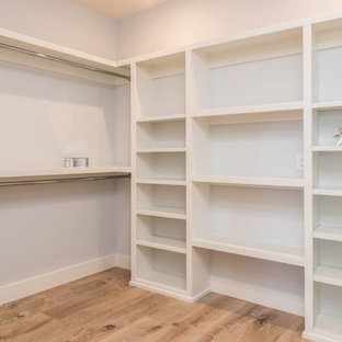 Diseño de armario vestidor unisex, clásico renovado, grande, con armarios abiertos, puertas de armario blancas y suelo de madera clara