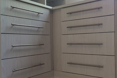 Ejemplo de armario vestidor clásico renovado grande con puertas de armario blancas, suelo de madera clara y suelo beige