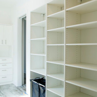 Immagine di una grande cabina armadio unisex contemporanea con ante lisce, ante bianche e pavimento grigio