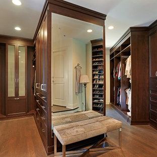 Idee per una grande cabina armadio unisex classica con ante in legno bruno, pavimento in legno massello medio e ante con riquadro incassato