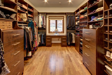 Modelo de armario vestidor unisex tradicional grande con armarios con paneles lisos, puertas de armario de madera en tonos medios, suelo de madera en tonos medios y suelo beige