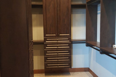 Modelo de armario vestidor unisex tradicional extra grande con armarios con paneles con relieve, puertas de armario de madera en tonos medios, moqueta y suelo beige