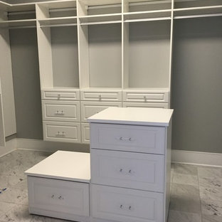 Diseño de armario vestidor unisex, tradicional, extra grande, con armarios con paneles con relieve, puertas de armario blancas y suelo de mármol
