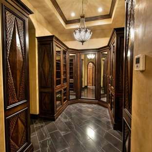 Idee per una cabina armadio per uomo chic di medie dimensioni con ante con bugna sagomata, ante in legno scuro e pavimento in ardesia