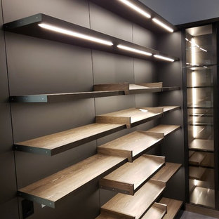 Idee per una grande cabina armadio unisex minimal con ante lisce, ante in legno scuro, pavimento in cemento e pavimento nero