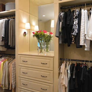 Exemple d'un grand dressing chic pour une femme avec un placard avec porte à panneau surélevé, des portes de placard blanches et un sol en bois foncé.