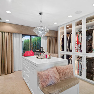 Inspiration for a tropical women's carpeted and beige floor dressing room remodel in Orange County with glass-front cabinets and white cabinets