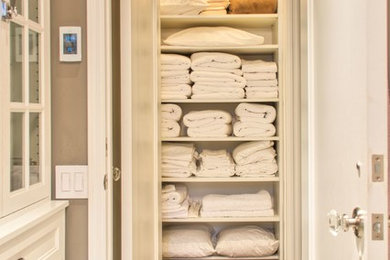 Diseño de armario unisex tradicional pequeño con armarios abiertos, puertas de armario blancas y suelo de madera en tonos medios