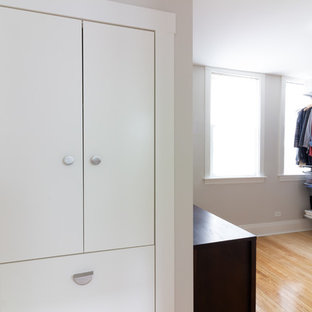 Immagine di una cabina armadio unisex nordica con ante lisce, ante bianche, parquet chiaro e pavimento giallo
