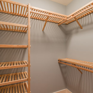 Ispirazione per una cabina armadio unisex american style di medie dimensioni con ante con bugna sagomata, ante in legno chiaro e parquet scuro