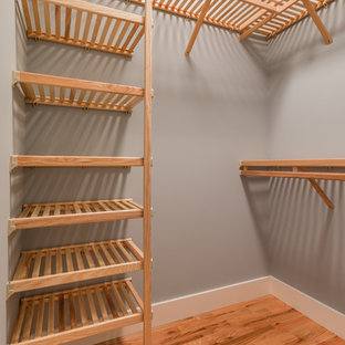 Esempio di una cabina armadio unisex stile americano di medie dimensioni con ante con bugna sagomata, ante in legno chiaro e parquet scuro