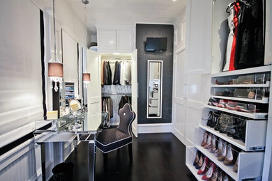 This is an example of a traditional dressing room for women in Austin with glass-front cabinets, white cabinets and dark hardwood flooring.