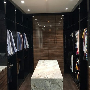 Esempio di una cabina armadio unisex contemporanea di medie dimensioni con ante lisce, ante in legno scuro, pavimento in legno massello medio e pavimento marrone