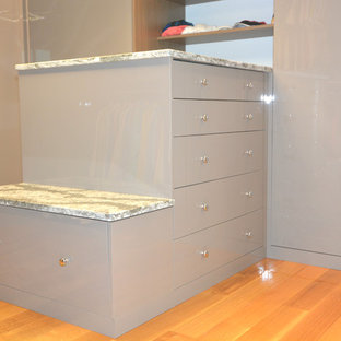 Modelo de armario vestidor unisex, moderno, de tamaño medio, con armarios con paneles lisos, puertas de armario beige, suelo de madera en tonos medios y suelo marrón
