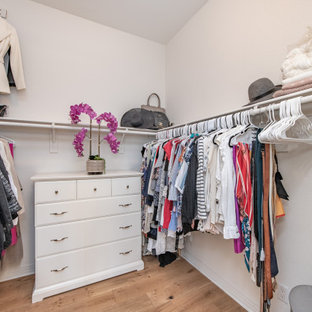 Immagine di un'ampia cabina armadio per donna mediterranea con ante lisce, ante bianche, parquet chiaro e pavimento beige
