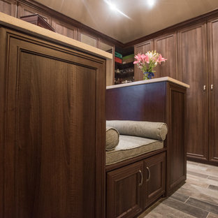 Esempio di una grande cabina armadio unisex tradizionale con ante con bugna sagomata, ante in legno scuro, pavimento in compensato e pavimento marrone