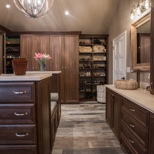 Foto di una grande cabina armadio unisex tradizionale con ante con bugna sagomata, ante in legno scuro, pavimento in compensato e pavimento marrone