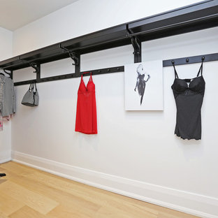 Imagen de armario vestidor unisex, escandinavo, de tamaño medio, con armarios abiertos, puertas de armario de madera en tonos medios y suelo de madera clara