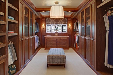 Example of a large classic gender-neutral carpeted walk-in closet design in New York with recessed-panel cabinets and medium tone wood cabinets
